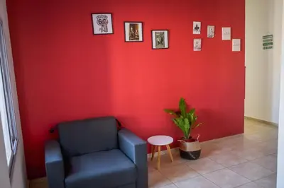 a waiting room with a chair and a red wall at Dpto con Balcón- Rafael Nuñez - Cerro de las Rosas in Cordoba