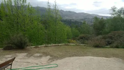 a garden with a green hose on the ground at Casona Familiar en La Cumbrecita in La Cumbrecita