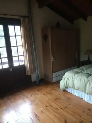 a bedroom with a bed and a large window at Casona Familiar en La Cumbrecita in La Cumbrecita