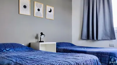 a bedroom with two beds with blue comforters and a window at Puerto del Aguila potrero de Garay Inbalo 01 in Los Reartes