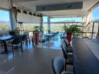 a dining room with tables and chairs and windows at ERNESTINA VILLAGE Resort Apart & suites in Villa Carlos Paz