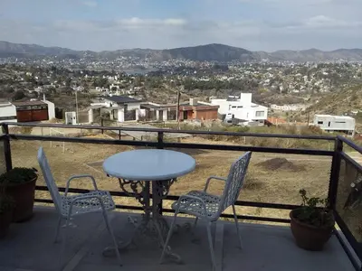 a table and chairs on a balcony with a view at ERNESTINA VILLAGE Resort Apart & suites in Villa Carlos Paz