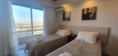 a room with two beds and a window with a view at ERNESTINA VILLAGE Resort Apart & suites in Villa Carlos Paz