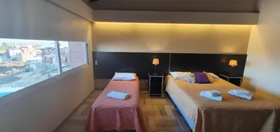 a hotel room with two beds and a large window at ERNESTINA VILLAGE Resort Apart & suites in Villa Carlos Paz