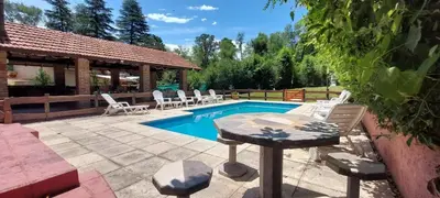 a swimming pool with chairs and a table next to it at La Palapa ApartHotel in Villa General Belgrano
