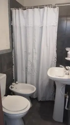 a white shower curtain in a bathroom with a toilet and sink at Duplex, Córdoba zona norte in Cordoba