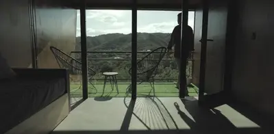 a man standing on a balcony looking out at the view at NIDO ARRIBA CABAÑAS in La Bolsa