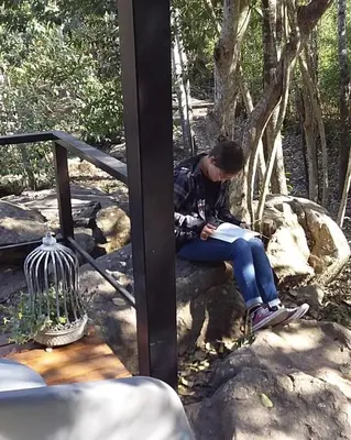 a woman sitting on a rock reading a book at Torito's House 1 in Tanti