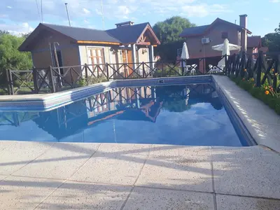 a swimming pool in front of a house at Cabañas Ruphay in Santa Rosa de Calamuchita