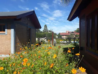 a garden with orange and yellow flowers next to a building at Cabañas Ruphay in Santa Rosa de Calamuchita