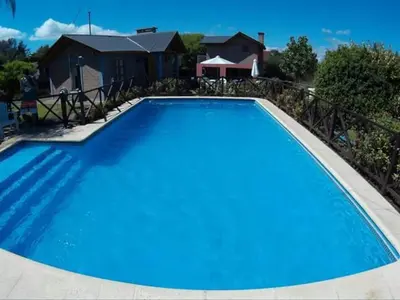 a large blue swimming pool in front of a house at Cabañas Ruphay in Santa Rosa de Calamuchita