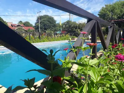a view from the garden of the pool and flowers at Cabañas Ruphay in Santa Rosa de Calamuchita