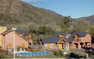 a house with a swimming pool in front of a mountain at Cabañas Ruphay in Santa Rosa de Calamuchita