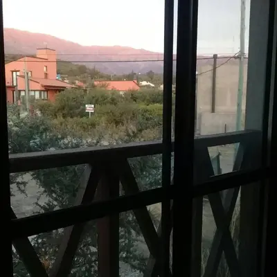 a window with a view of a field and buildings at Hotel posada barrancas del sol in Merlo