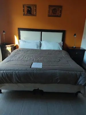 a large bed in a bedroom with an orange wall at Hotel posada barrancas del sol in Merlo