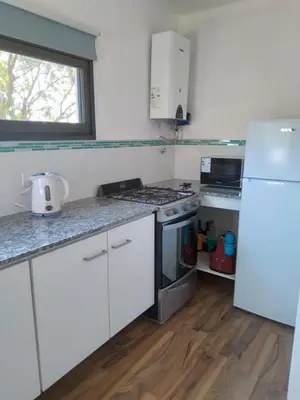 a kitchen with white cabinets and a white refrigerator at Cabañas Tierra Kamiare 2 in Villa Amancay