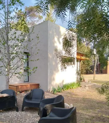 a white building with chairs and a bench in a yard at Cabañas Tierra Kamiare 2 in Villa Amancay