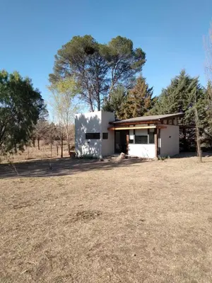 a small white building with a tree in the background at Cabañas Tierra Kamiare 2 in Villa Amancay