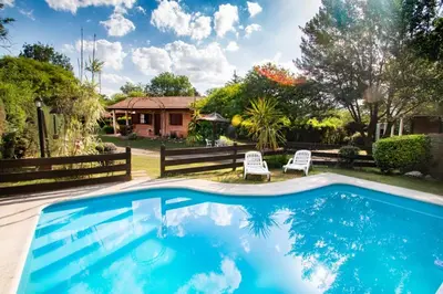 a pool in a yard with two chairs and a house at Der Wandel in Villa General Belgrano