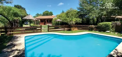 a blue swimming pool in a yard with a fence at Der Wandel in Villa General Belgrano