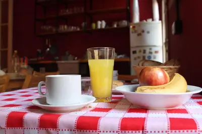 a table with a plate of fruit and a cup of orange juice at CASA ARTIGAS Hostel in Cordoba