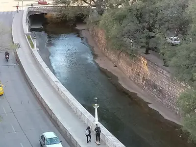 two people walking on a bridge over a river at hermoso Dpto. sobre La cañada en el centro de Córdoba capital-Argentina in Cordoba
