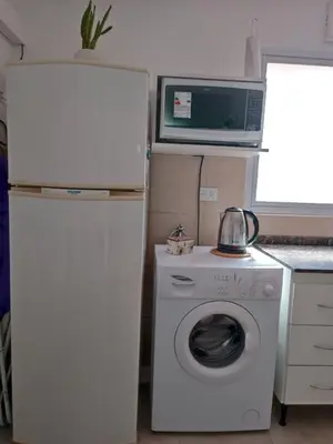 a small kitchen with a refrigerator and a washing machine at AA Departamento Flat Premium Córdoba in Cordoba