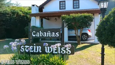 a sign in front of a white house at Cabañas Stein Weiss in Santa Rosa de Calamuchita