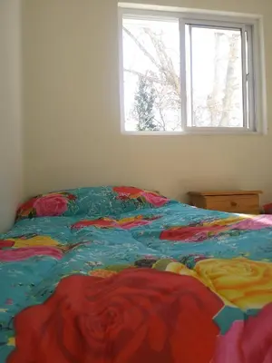 a bed with a colorful comforter in a room with a window at Casa de Vacaciones in Santa Rosa de Calamuchita
