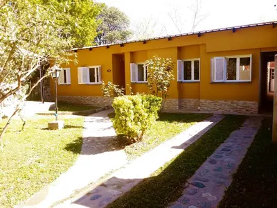 a yellow house with a pathway in front of it at Casa de Vacaciones in Santa Rosa de Calamuchita
