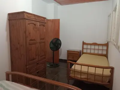 a bedroom with a bed and a wooden cabinet at Casa de Vacaciones in Santa Rosa de Calamuchita