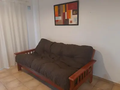 a brown couch sitting under a painting on a wall at Plaza Rivadavia Departamento in Cordoba