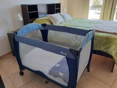 a small blue crib in a room with a bed at Plaza Rivadavia Departamento in Cordoba