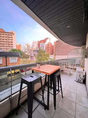 a wooden table and two stools on a balcony at Departamento Ecofriendly excelente ubicación in Cordoba