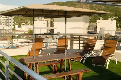 a picnic table and chairs under an umbrella on a roof at Departamentos Premium Miralejos 3 in Villa Carlos Paz