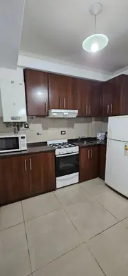 a kitchen with wooden cabinets and a white refrigerator at Departamentos Premium Miralejos 3 in Villa Carlos Paz