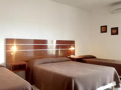 a hotel room with two beds and two tables at Hotel Ritz in Alta Gracia