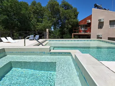 a swimming pool with blue water in front of a building at COSTA COM Apart Suites in Merlo