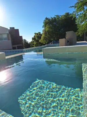a swimming pool with clear blue water and trees at COSTA COM Apart Suites in Merlo