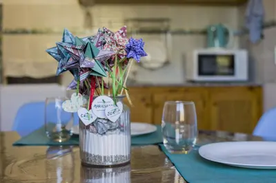 a vase of flowers on a table with two glasses at COSTA COM Apart Suites in Merlo