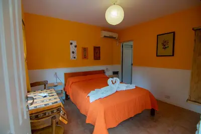 a bedroom with two beds with orange walls at El Viejo Algarrobo - Hosteria Serrana in Merlo