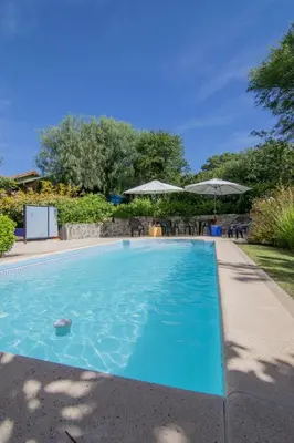 a blue swimming pool with chairs and umbrellas at El Viejo Algarrobo - Hosteria Serrana in Merlo