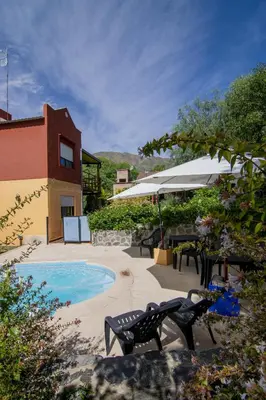a pool with chairs and umbrellas next to a building at El Viejo Algarrobo - Hosteria Serrana in Merlo