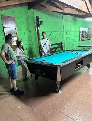 a group of people standing around a pool table at Apart Cabañas Oasis del Valle in Villa Cura Brochero