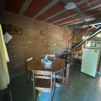 a kitchen with a wooden table and a refrigerator at Apart Cabañas Oasis del Valle in Villa Cura Brochero