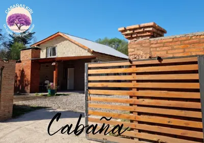 a house with a wooden fence in front of it at Cabañas Kiri in Santa Rosa de Calamuchita