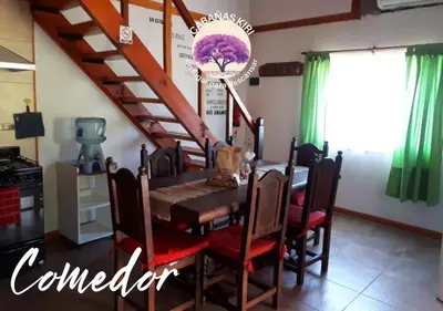 a dining room with a table and a staircase at Cabañas Kiri in Santa Rosa de Calamuchita