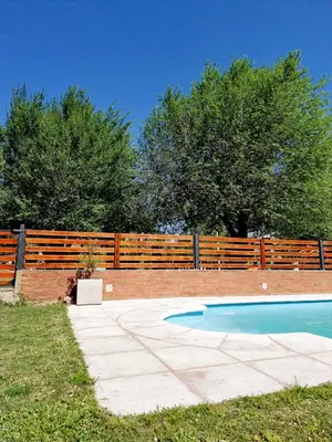 a swimming pool in front of a wooden fence at Cabañas Kiri in Santa Rosa de Calamuchita