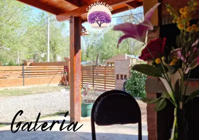 a chair sitting in front of a porch with flowers at Cabañas Kiri in Santa Rosa de Calamuchita