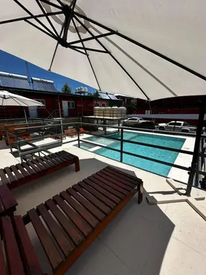 a swimming pool with two benches and an umbrella at La posta del vasco in Tanti